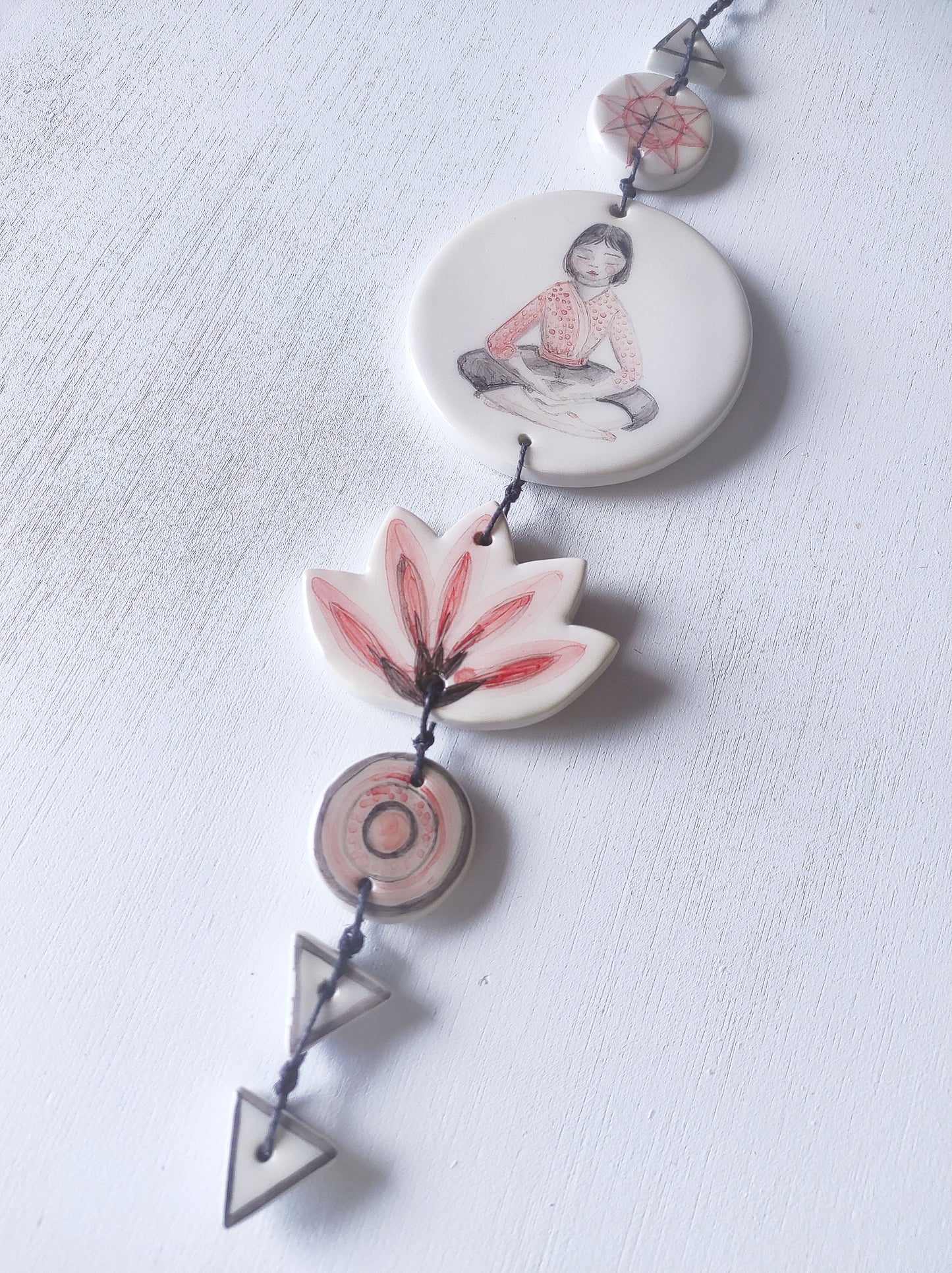 Detalle colgante pared loza esmaltada chica meditación rojo negro BIHU
