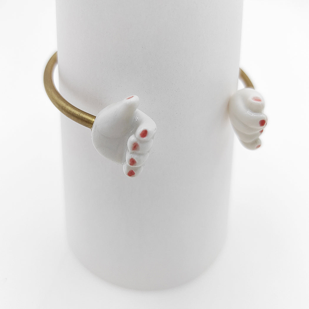 Detalle de pulsera abierta dos manos porcelana esmaltada y latón BIHU uñas rojas