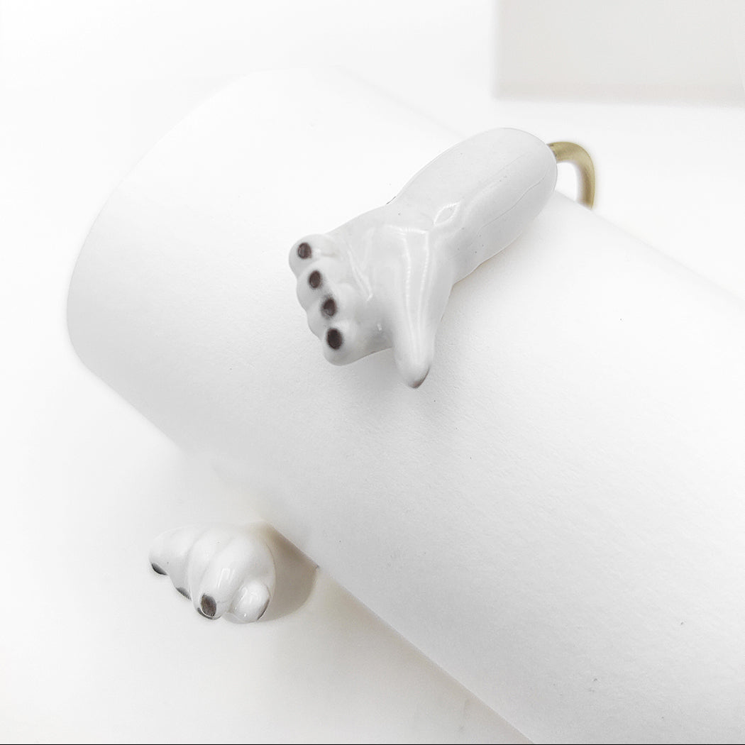 Detalle de pulsera abrazo porcelana esmaltada y latón BIHU con uñas pintadas de negro